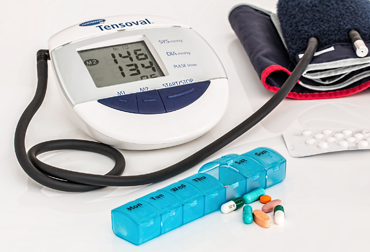 Blutdruckmessgerät zum Blutdruckmessen, eine Tablettenblister und eine Packung Tablette mit einzelnen Tabletten im Vordergrund.